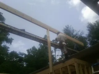 Carpenter setting a ridge beam over a new addition frame — Ice Dam Removal by Roofing Brothers in Reasnor