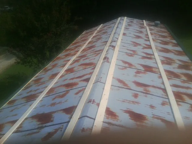 Rusted metal roof panels with new wood purlins before replacement — Storm Damage Roof Repair in Reasnor by Roofing Brothers