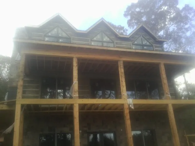 Dormers and porch framing on a large log home under construction — Roof Coating work by our crew in Reasnor
