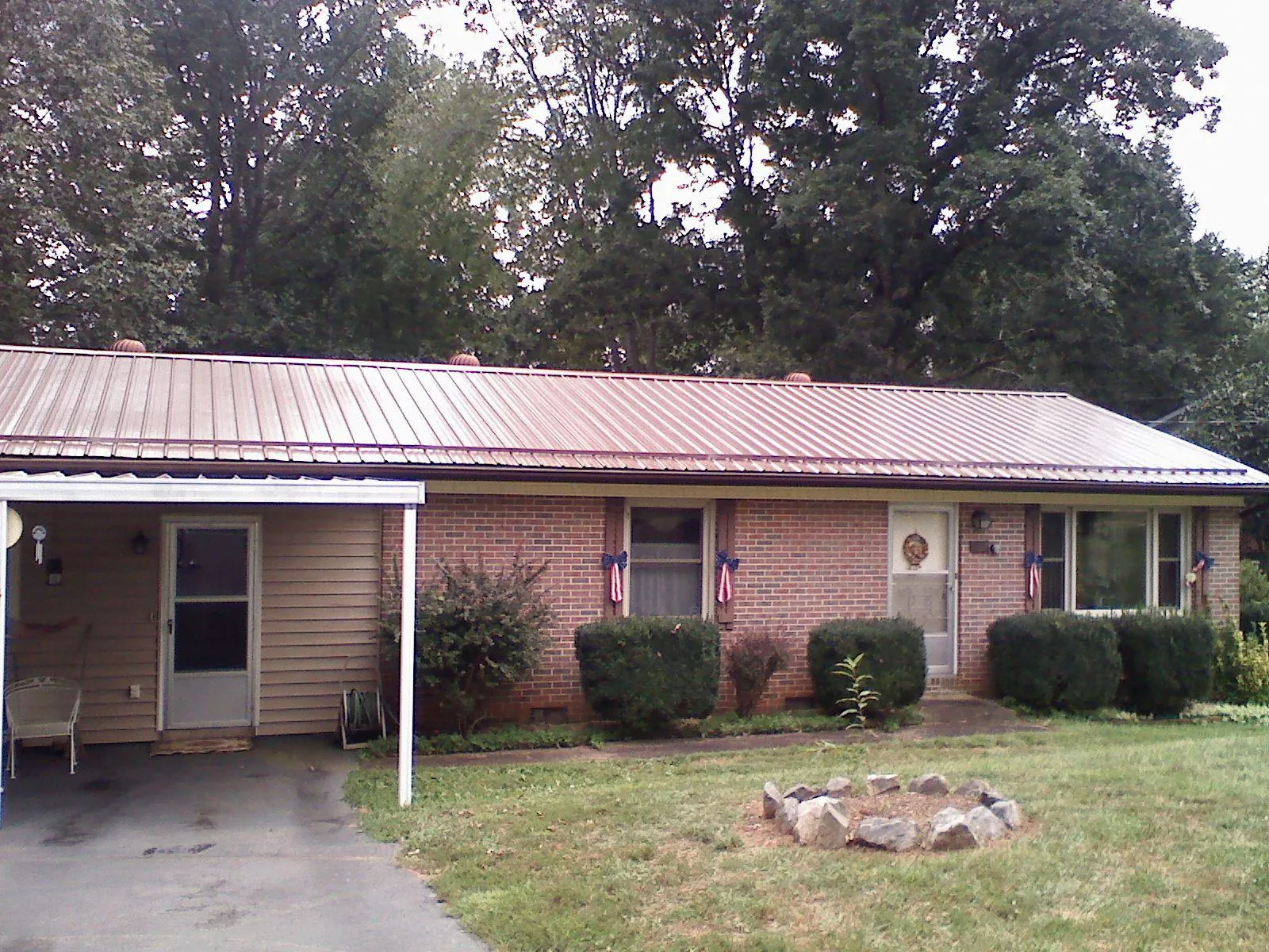 Bronze metal roof and carport on a brick ranch home — Roof Repair work by our crew in Reasnor