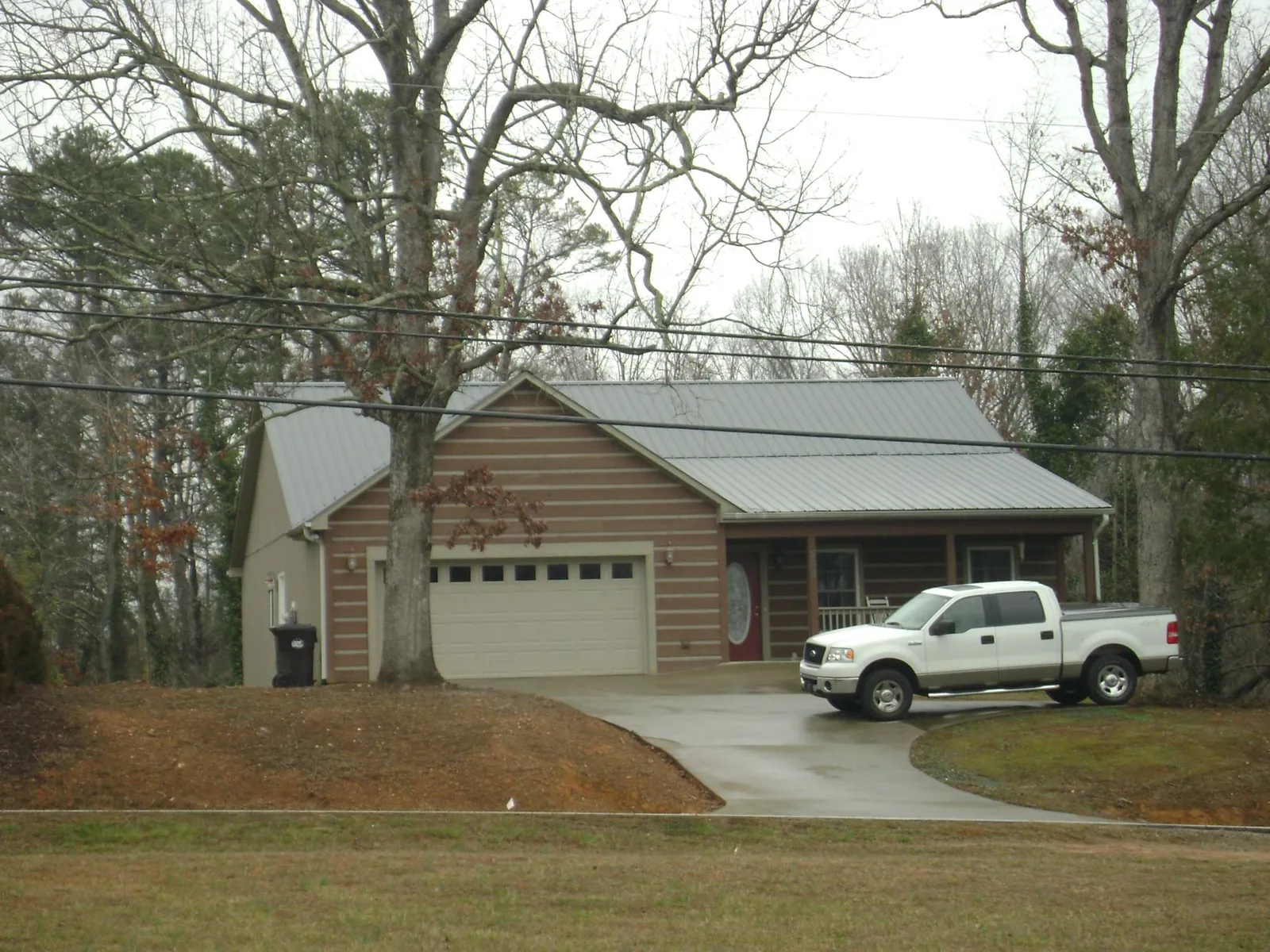 Gray metal roof on a log sided house with an attached two car garage in Reasnor
