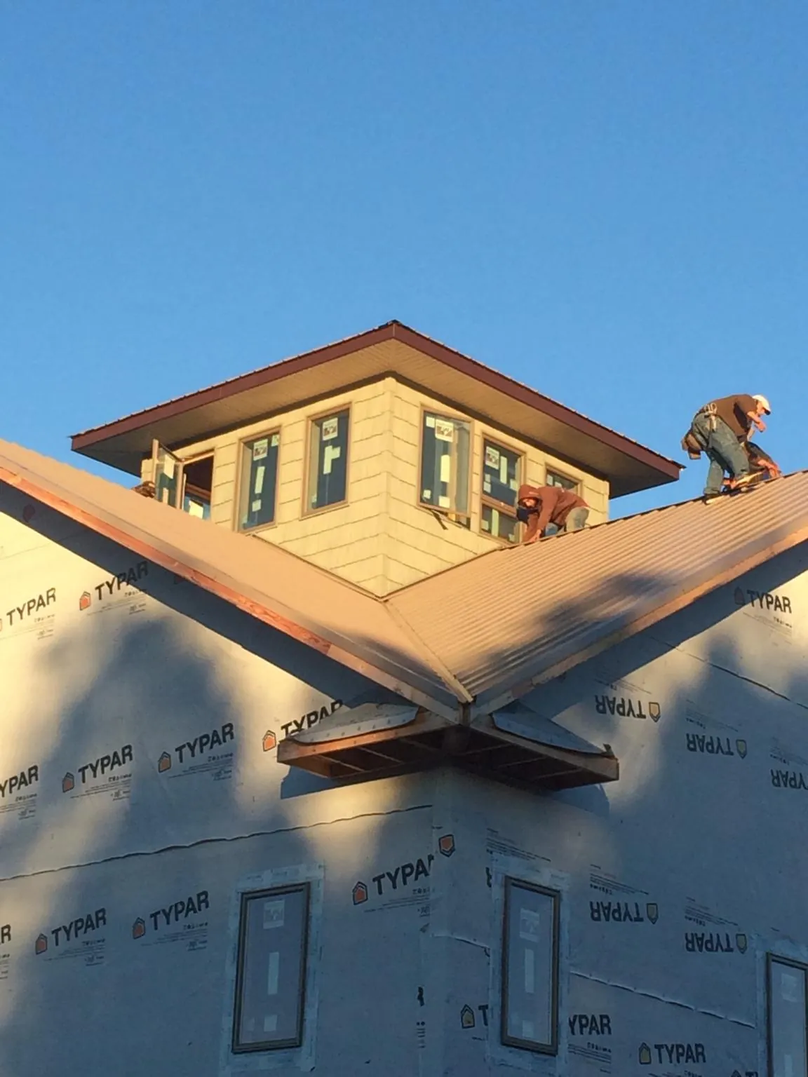 Roofers working around a rooftop cupola on a new metal roof at sunset — Roof Waterproofing in Reasnor by Roofing Brothers